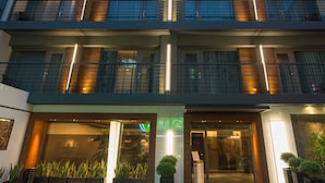 A multi-story hotel with balconies, a ground-level entrance, and a sign indicating a restaurant. - Simple Plus Hotel (Taipei)