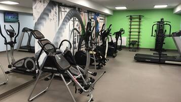 A gym with various exercise equipment, including treadmills, stationary bikes, and weight machines.