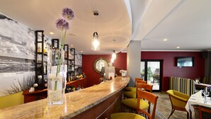 A bar area with a marble countertop, clear glass vase with flowers, and wooden chairs. - Hotel La Siesta (Wladyslawowo)