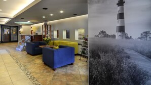 A lobby with a reception desk, sofas, a coffee table, a large painting of a lighthouse, and a tiled floor. - Hotel La Siesta (Wladyslawowo)