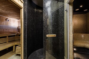 Un sauna avec des bancs en bois et un espace douche fermé par des parois de verre.