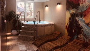 A spa area with a hot tub, wooden loungers, a staircase leading to the tub, and a large abstract painting on the wall. - Hotel La Siesta (Wladyslawowo)