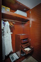 A wooden closet with shelves, a hanging rack, and a shoe rack.
