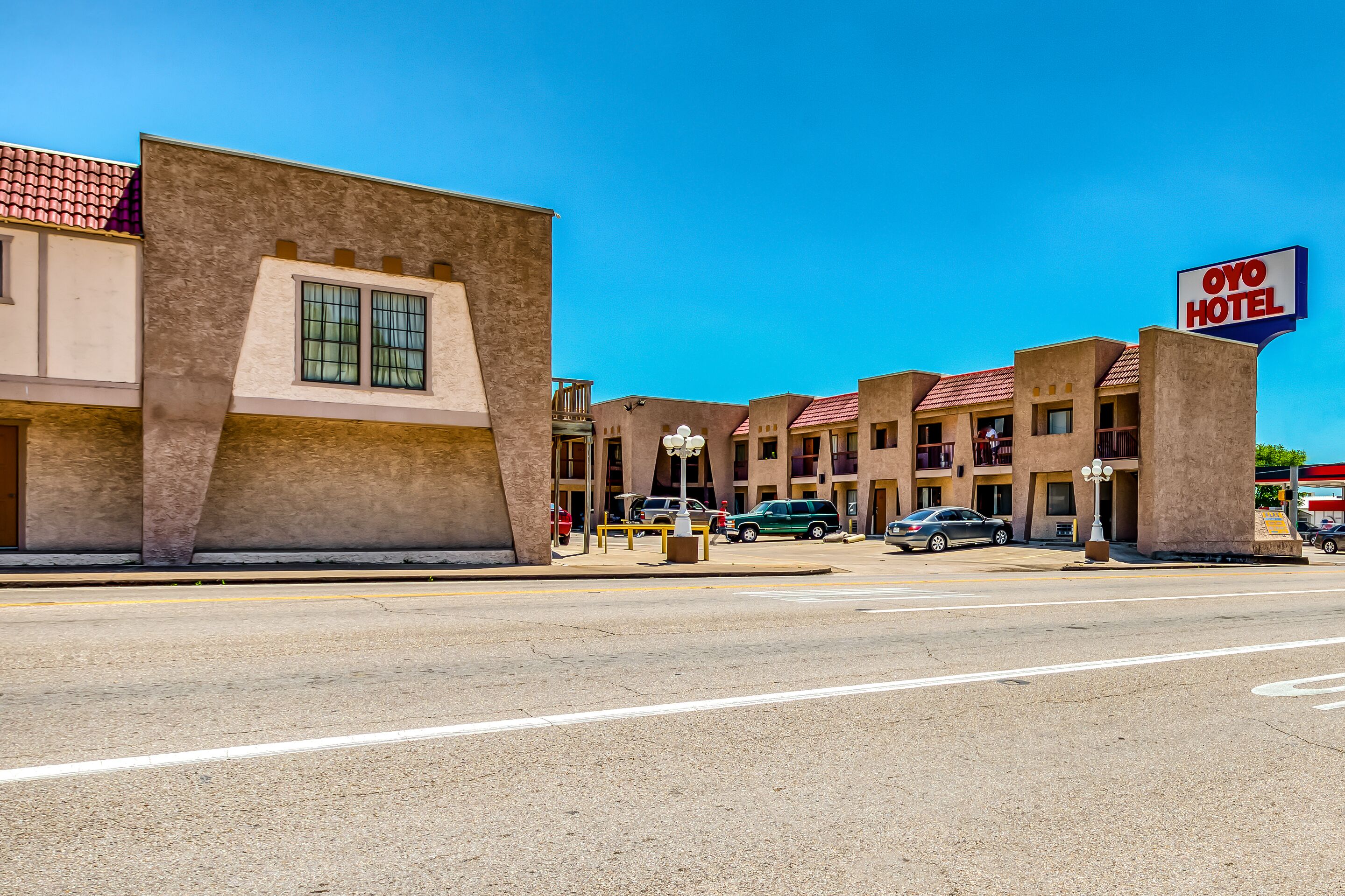 A hotel with a sign reading "OYO HOTEL" and a parking lot with several cars.