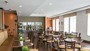 A restaurant with multiple tables and chairs, a bar area, and a kitchen in the background. - Sleep Inn & Suites Austin Northeast (Austin)