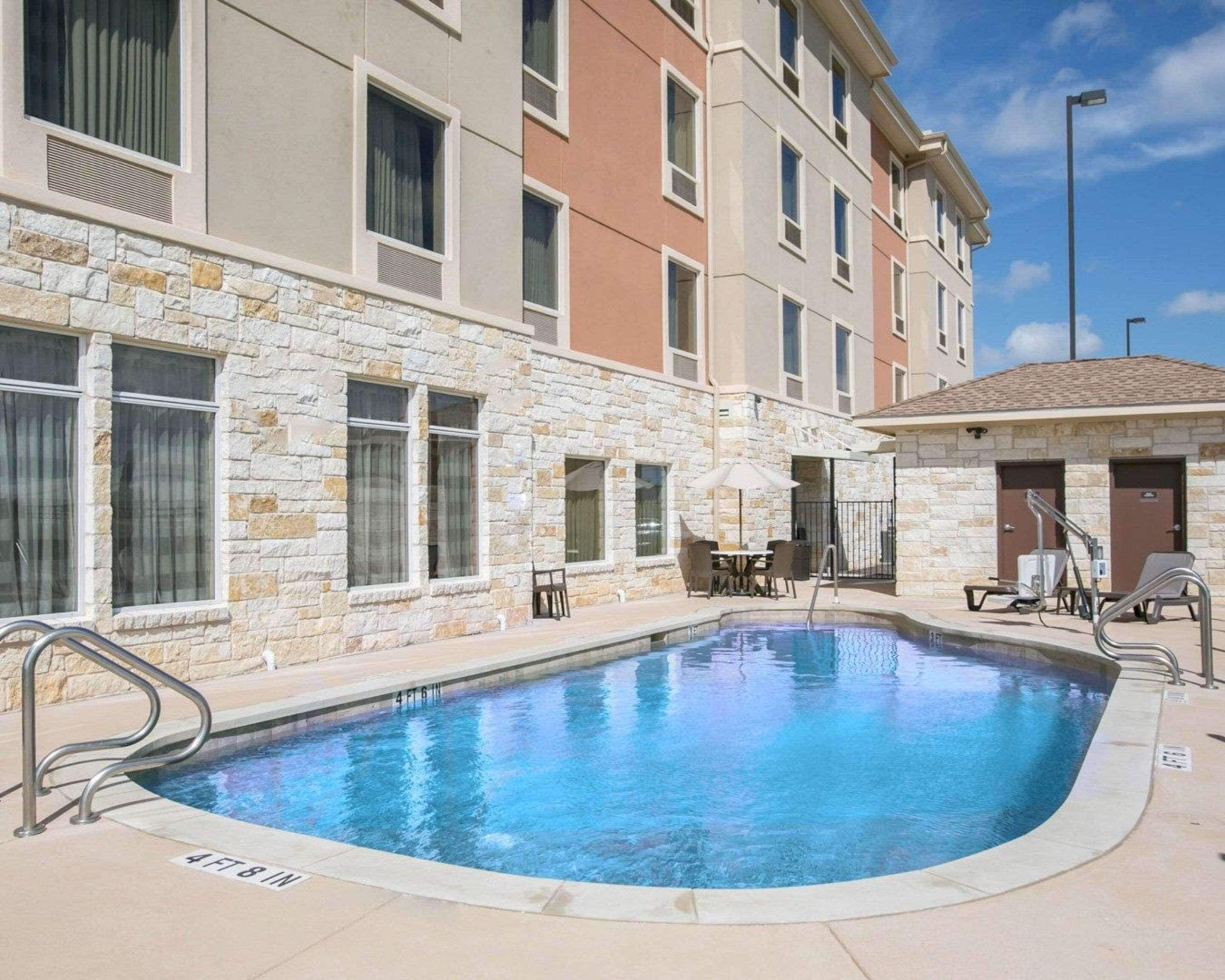 Una piscina con un muro de piedra y un edificio con varias ventanas y puertas.