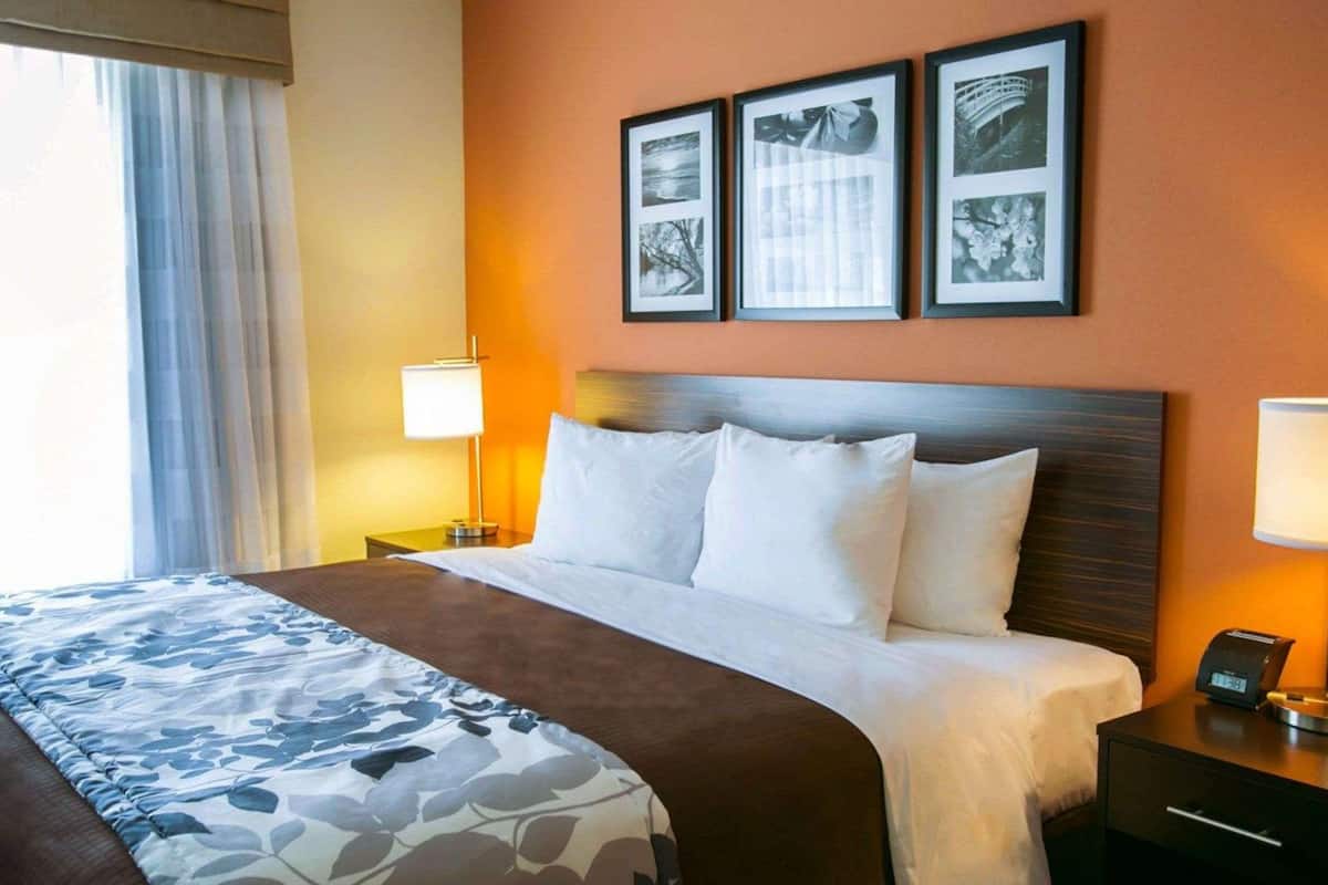 A hotel room with a bed, a nightstand with a lamp, and three framed pictures on the wall.