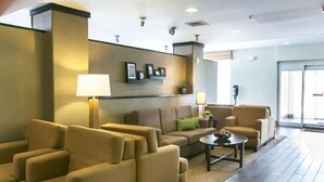 A modern lobby with a sofa set, a coffee table, and a wall-mounted shelf with framed pictures. - Sleep Inn & Suites Austin Northeast (Austin)