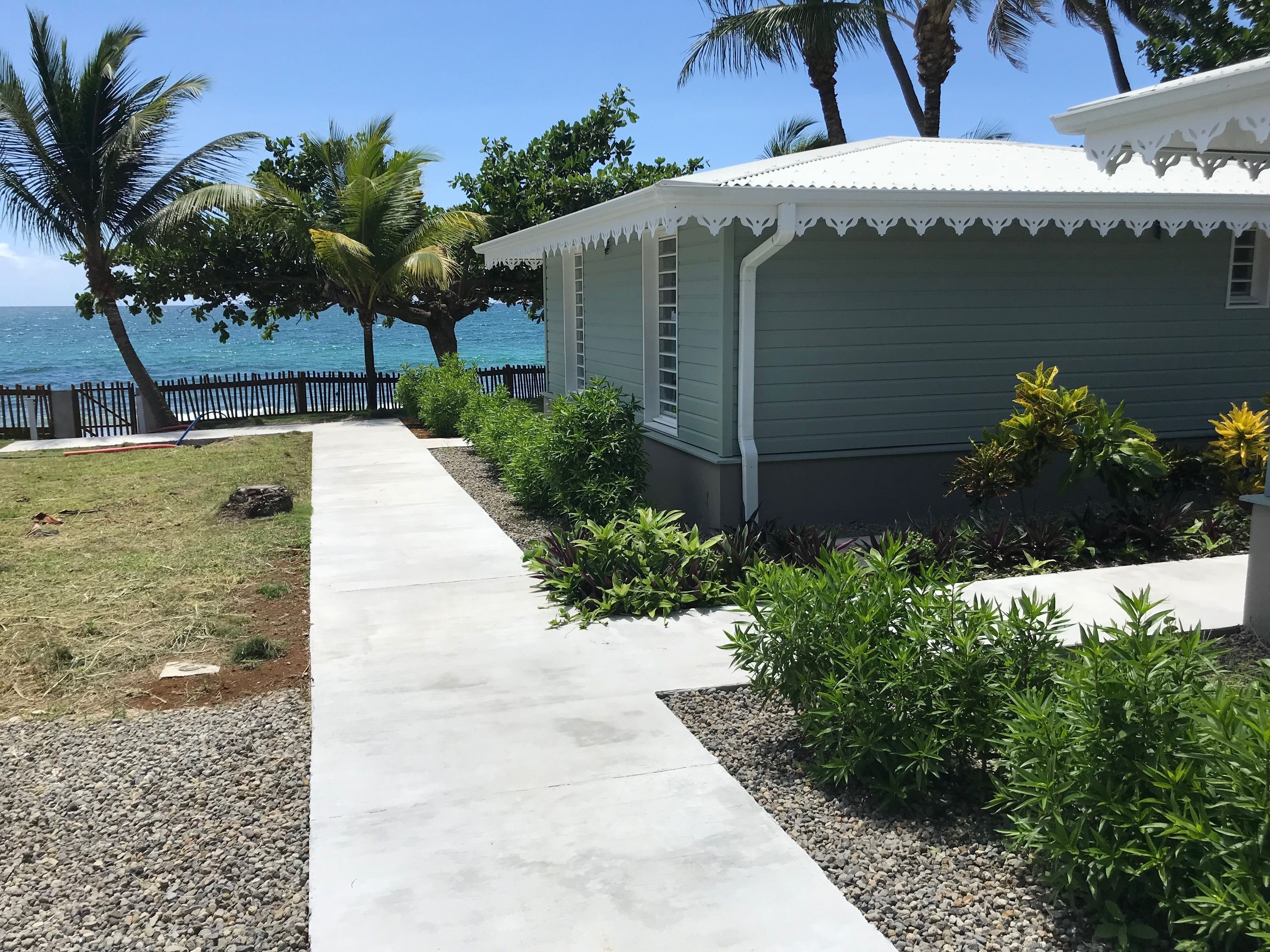 A house with a covered porch, a concrete pathway, and a view of the ocean.
