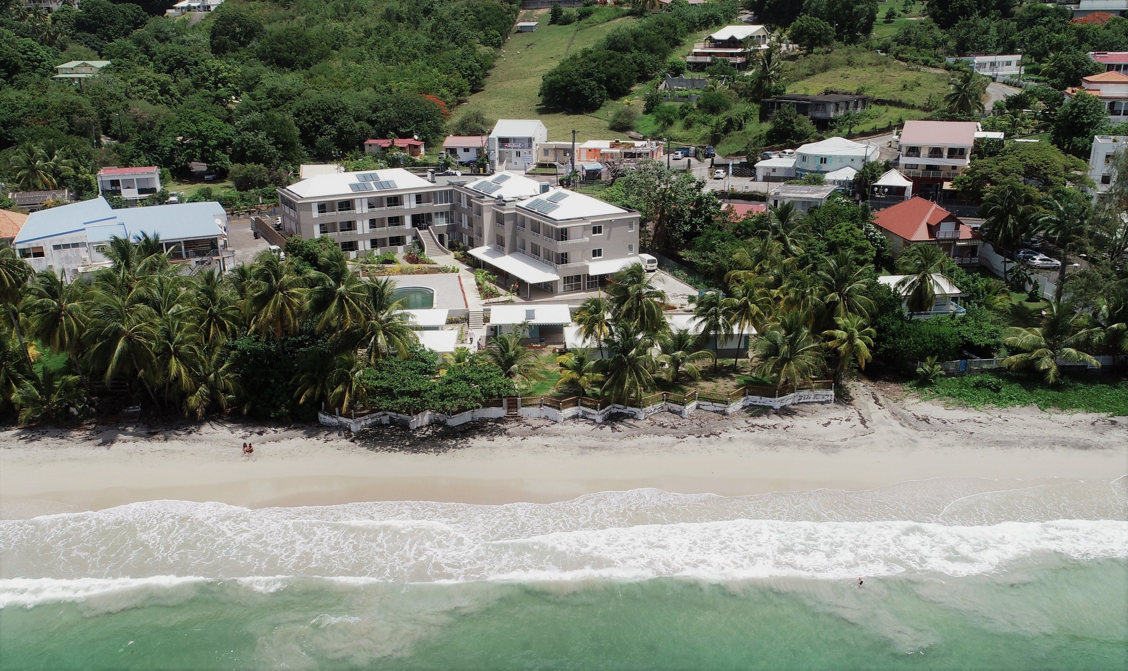 Zona residencial costera con edificios modernos, una playa de arena y palmeras.
