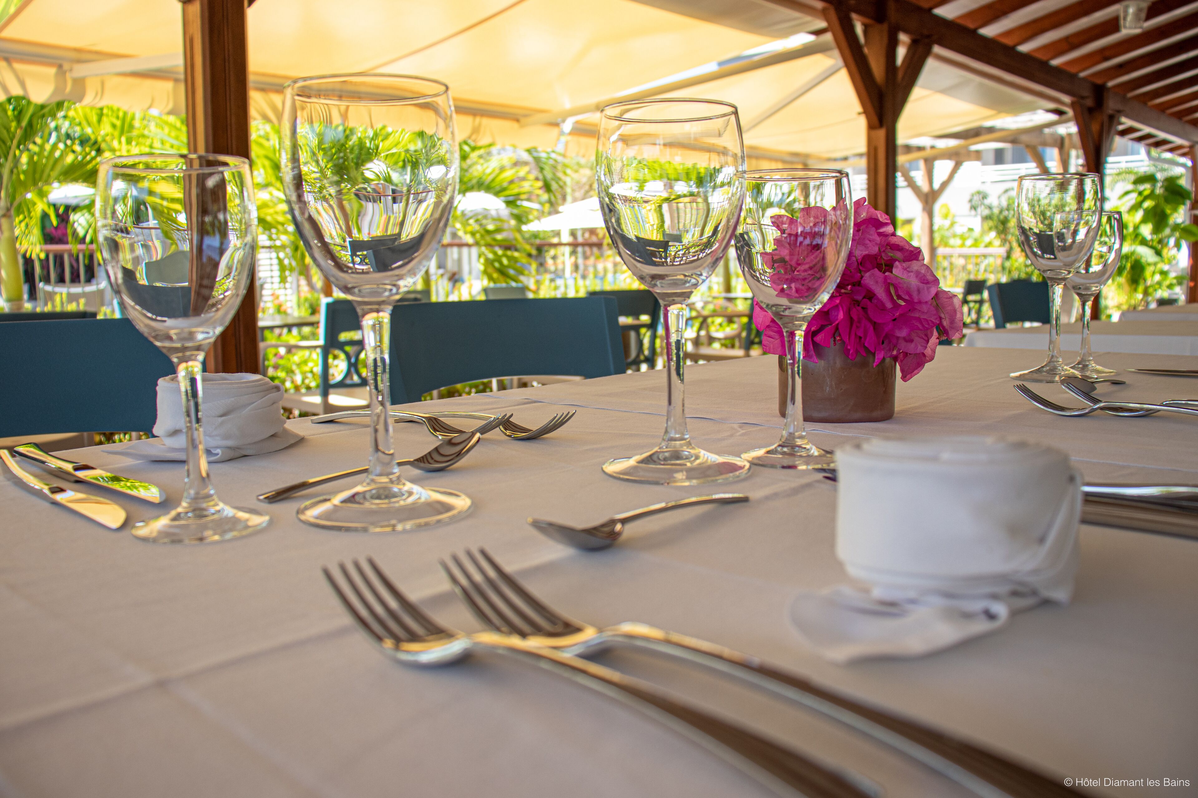 A table set for dining with wine glasses, cutlery, and a flower vase.