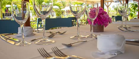 Une table mise pour le dîner, avec des verres à vin, des couverts et un vase de fleurs.