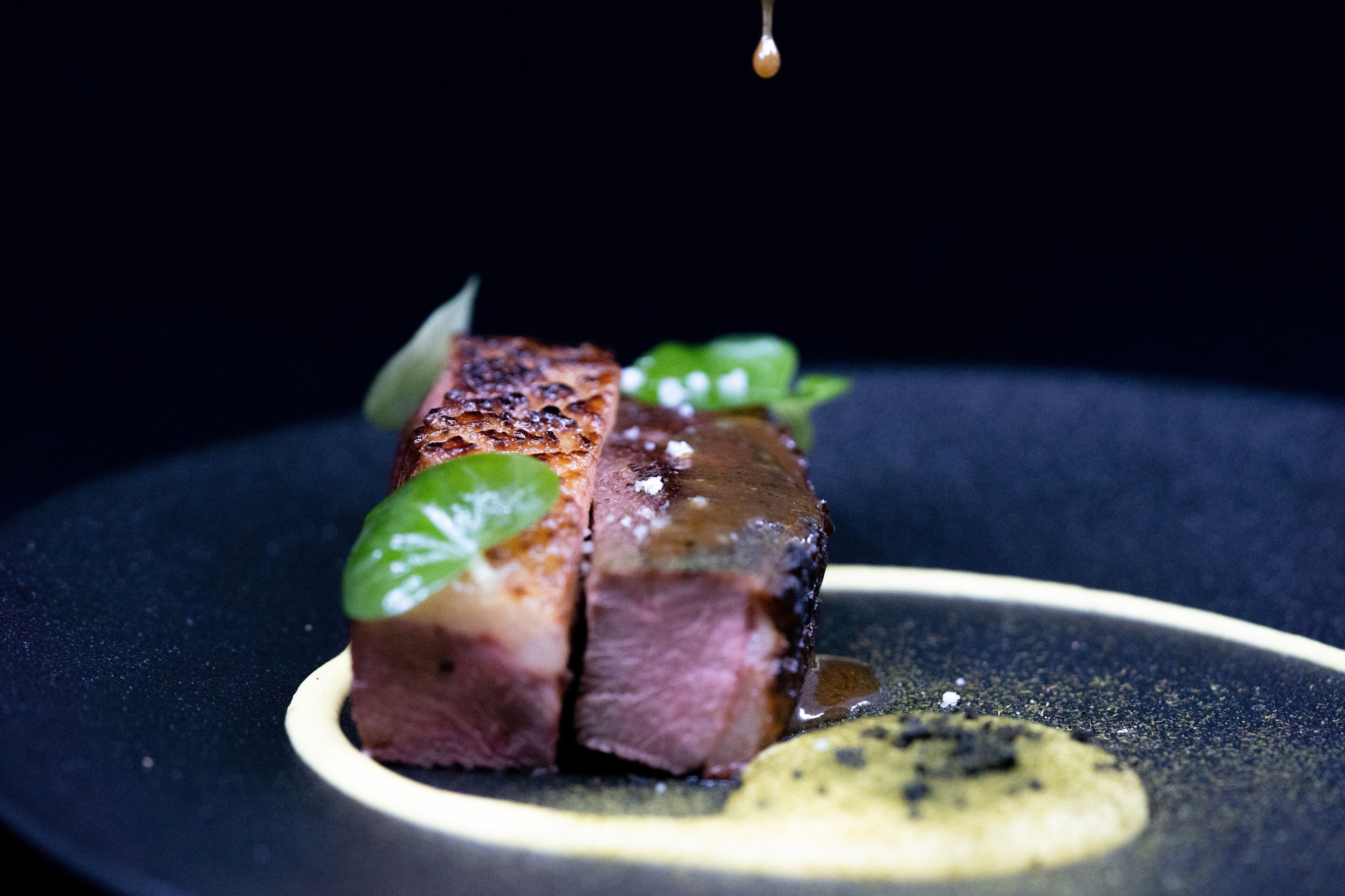 A close-up of a steak with a garnish on a plate.