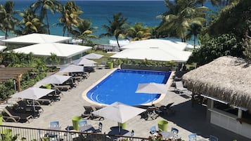 Alberca al aire libre, sombrillas en la alberca y camastros