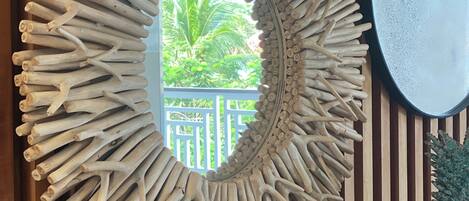 A wall with a circular mirror surrounded by a textured frame.