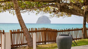 Ein Holzzaun, ein großer Pflanzkasten und Blick auf das Meer mit einer entfernten Insel.
