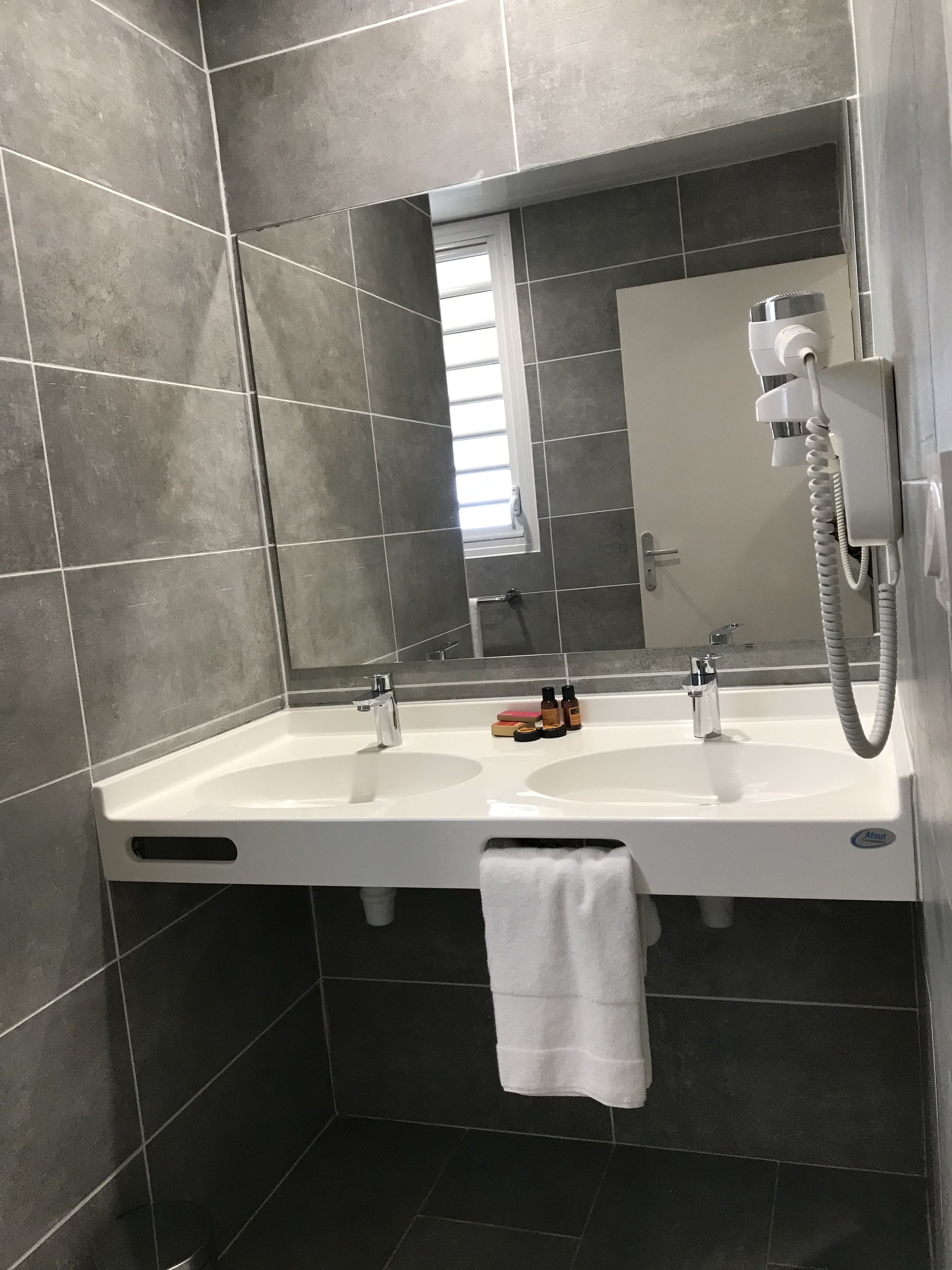 A bathroom with a double sink, a mirror, a towel rack, and a telephone.