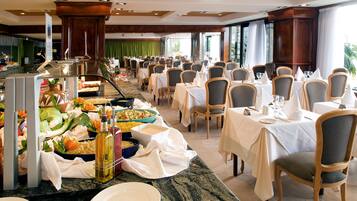 Un buffet proposant une variété de plats et de boissons, disposés sur un comptoir en marbre, avec des chaises et des tables préparées pour le repas.