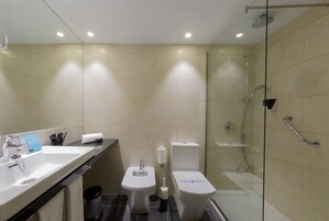 Un baño moderno con cabina de ducha de vidrio, un lavabo con espejo y dos inodoros.