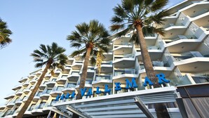 Un hotel de varios pisos con balcones y palmeras.
