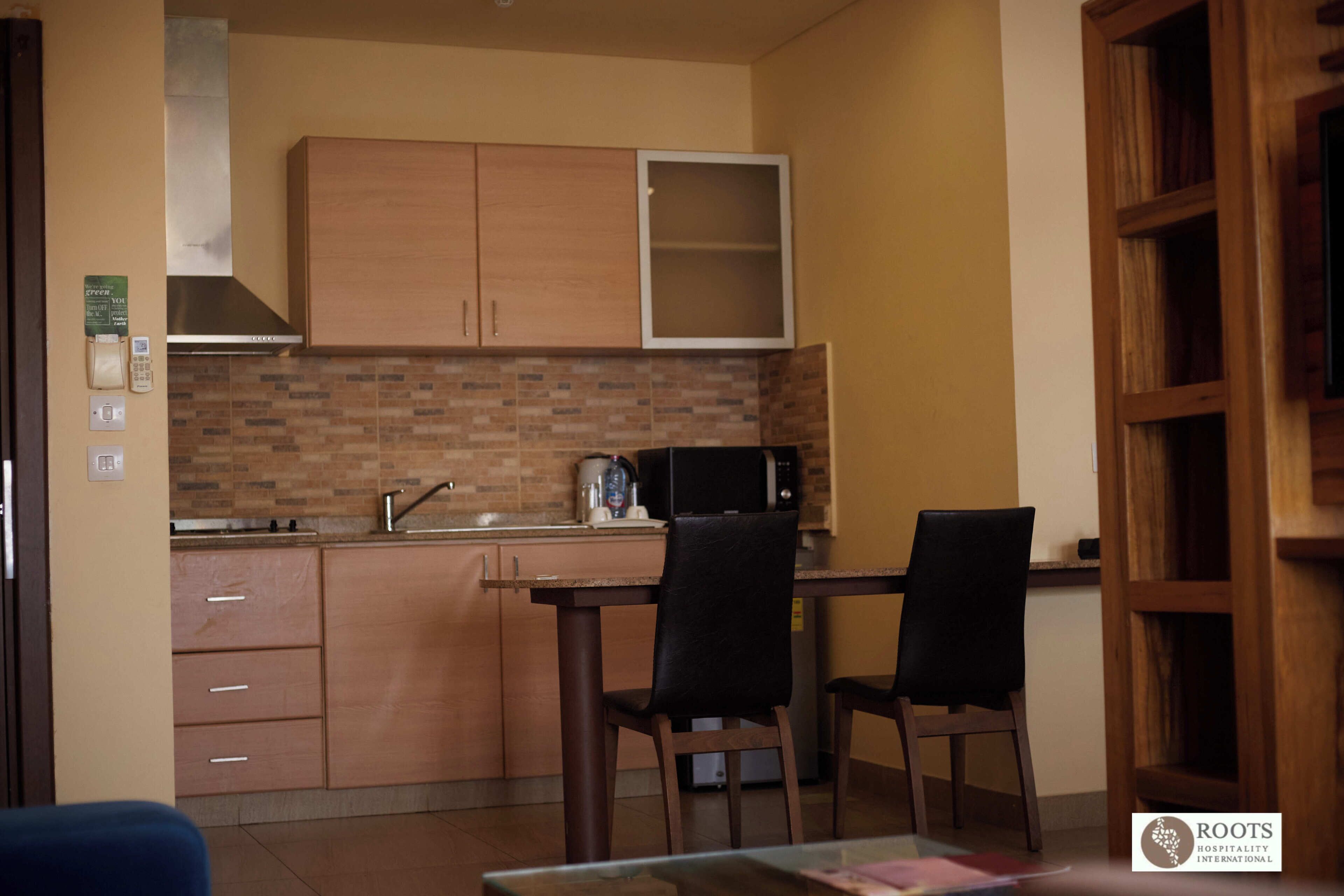 Una cucina funzionale con mobili in legno, un forno a microonde e una macchina da caffè. Sono presenti due sedie e un tavolo.