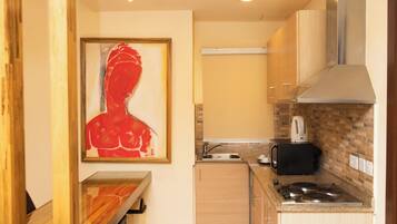 A compact kitchen with a dining area, a stove, a microwave, and a sink.