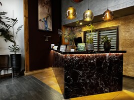 A reception area with a marble counter, potted plants, and hanging pendant lights.