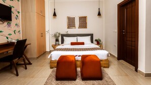 A bedroom with a bed, two bedside tables, a desk, and a chair. - Roots Hotel Apartment (Accra)