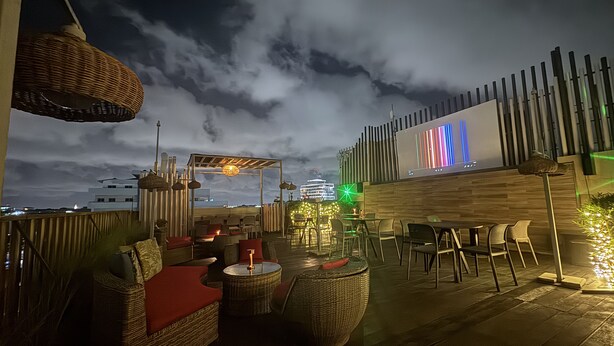 An outdoor seating area with wicker furniture and a wooden deck. - Roots Hotel Apartment (Accra)
