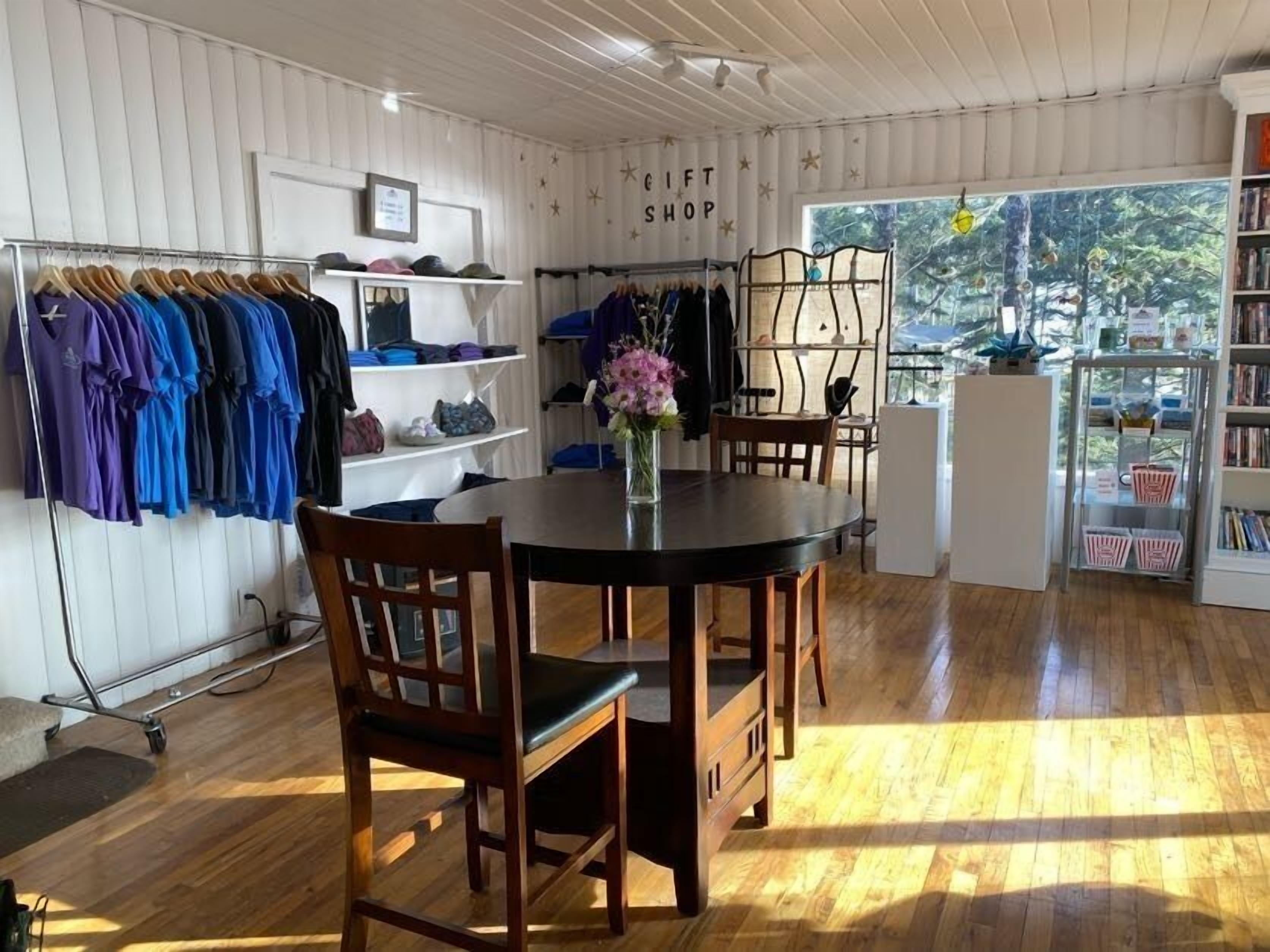 A room with a dining table, chairs, a clothing rack, and a bookshelf.