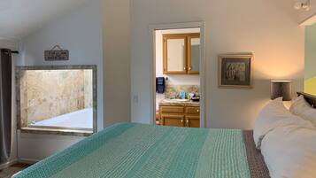 A bedroom with a large bed, a bathroom with a bathtub, and a view of the hallway.