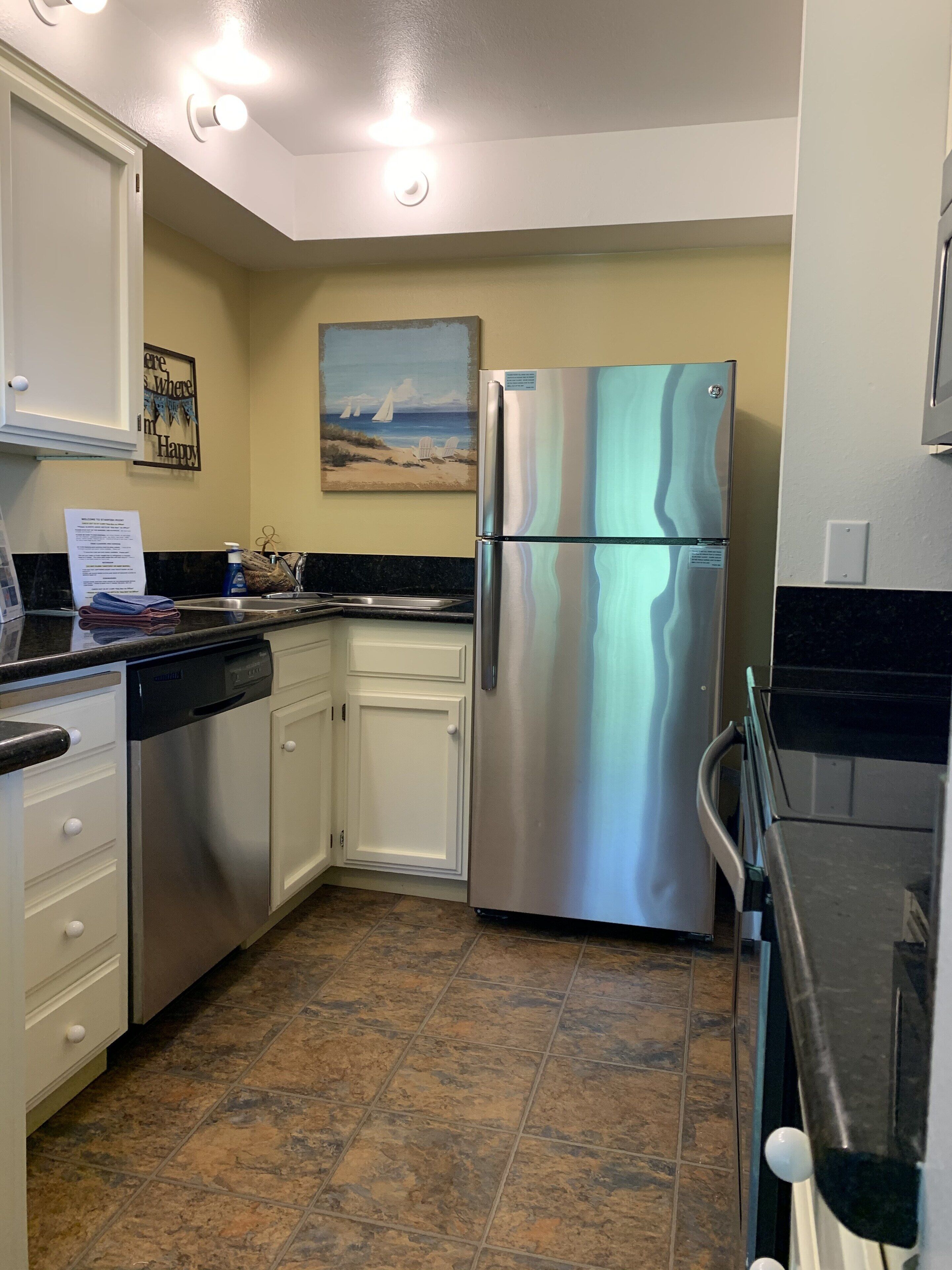 A kitchen with stainless steel appliances, white cabinets, and a tiled floor.