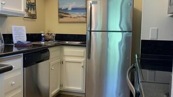 A kitchen with stainless steel appliances, white cabinets, and a tiled floor.