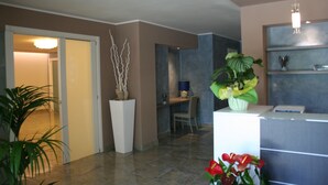 A modern reception area with a desk, chairs, and potted plants. - Apart Hotel Atlantic (Grado)