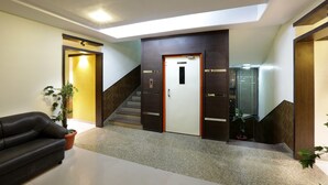 Un vestíbulo con una escalera, un mostrador de recepción y plantas en macetas.