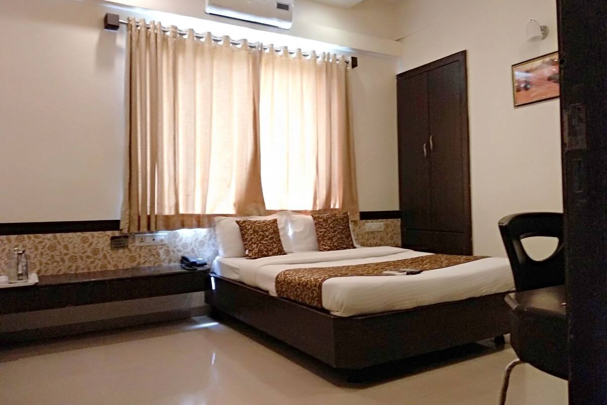 A hotel room with a bed, a wardrobe, a desk, and a chair.