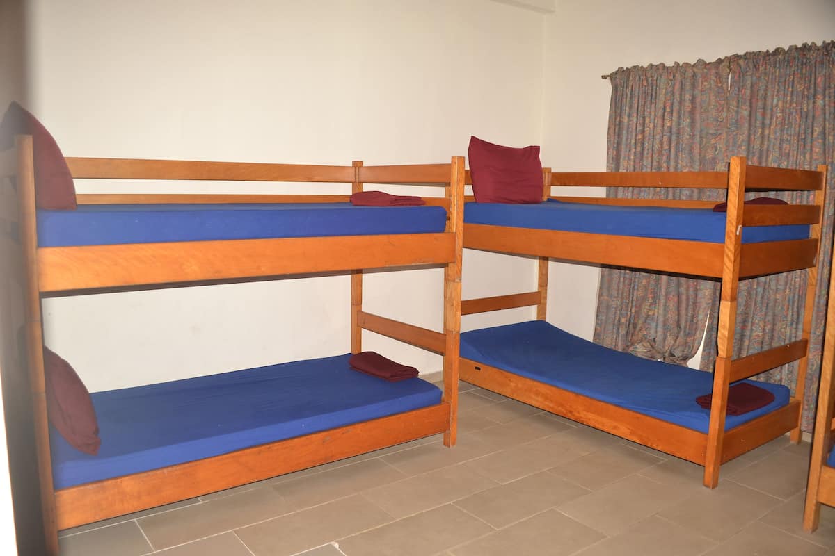 Quarto com duas beliches, cada uma com colchões azuis e almofadas vermelhas.