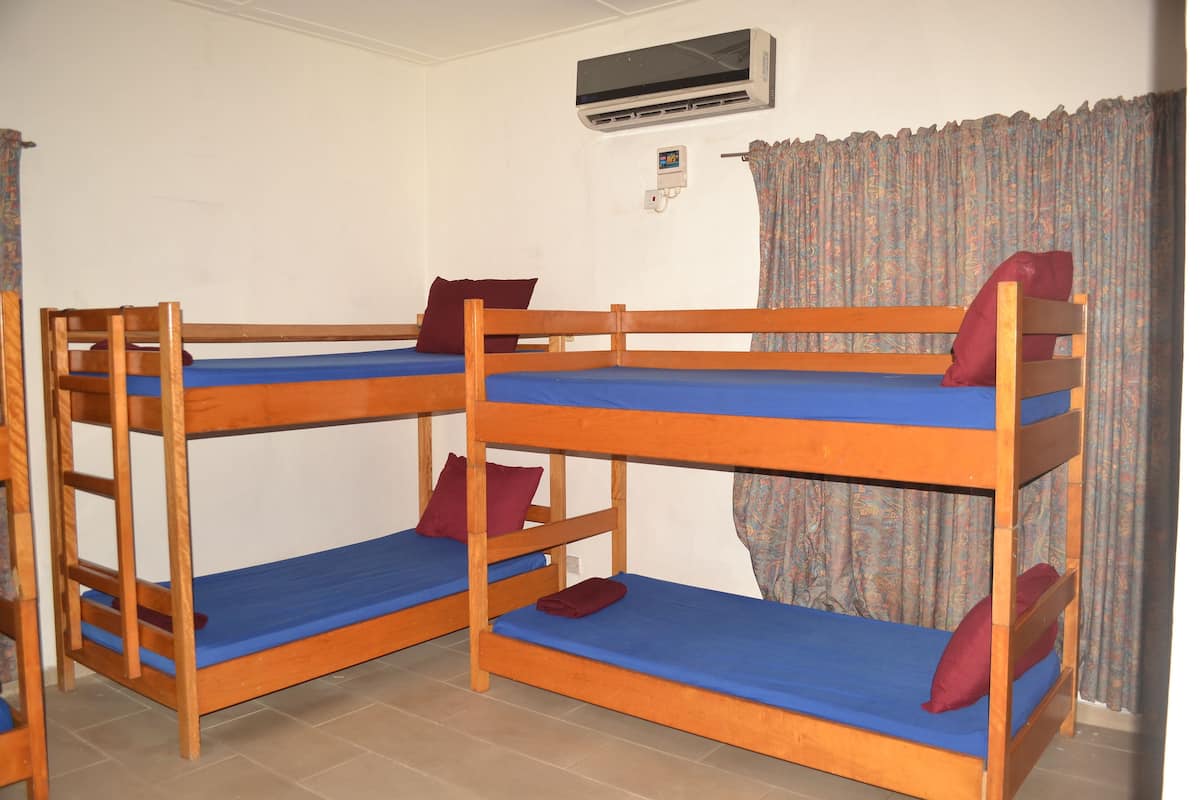Quarto com beliches, ar condicionado e cortina.