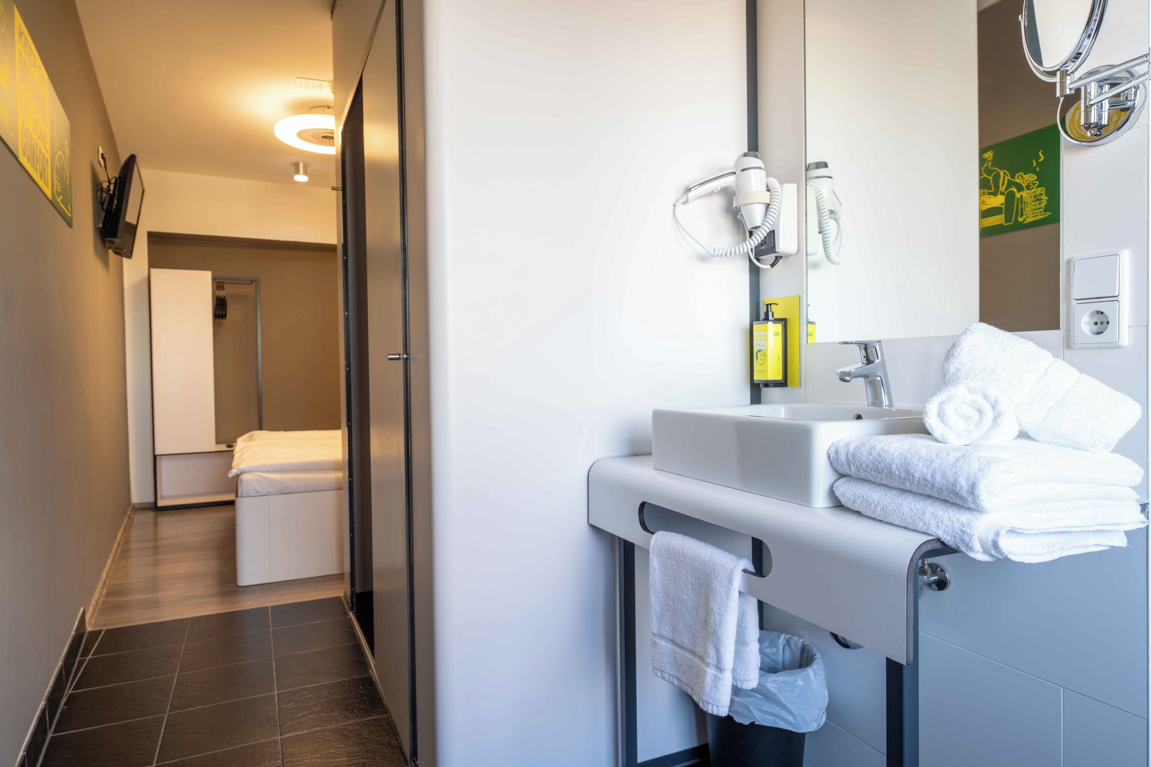 Un baño moderno con lavamanos, toallero y espejo.