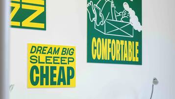 A bedroom with green and white bedding, a bed with two pillows, and three motivational posters on the wall.