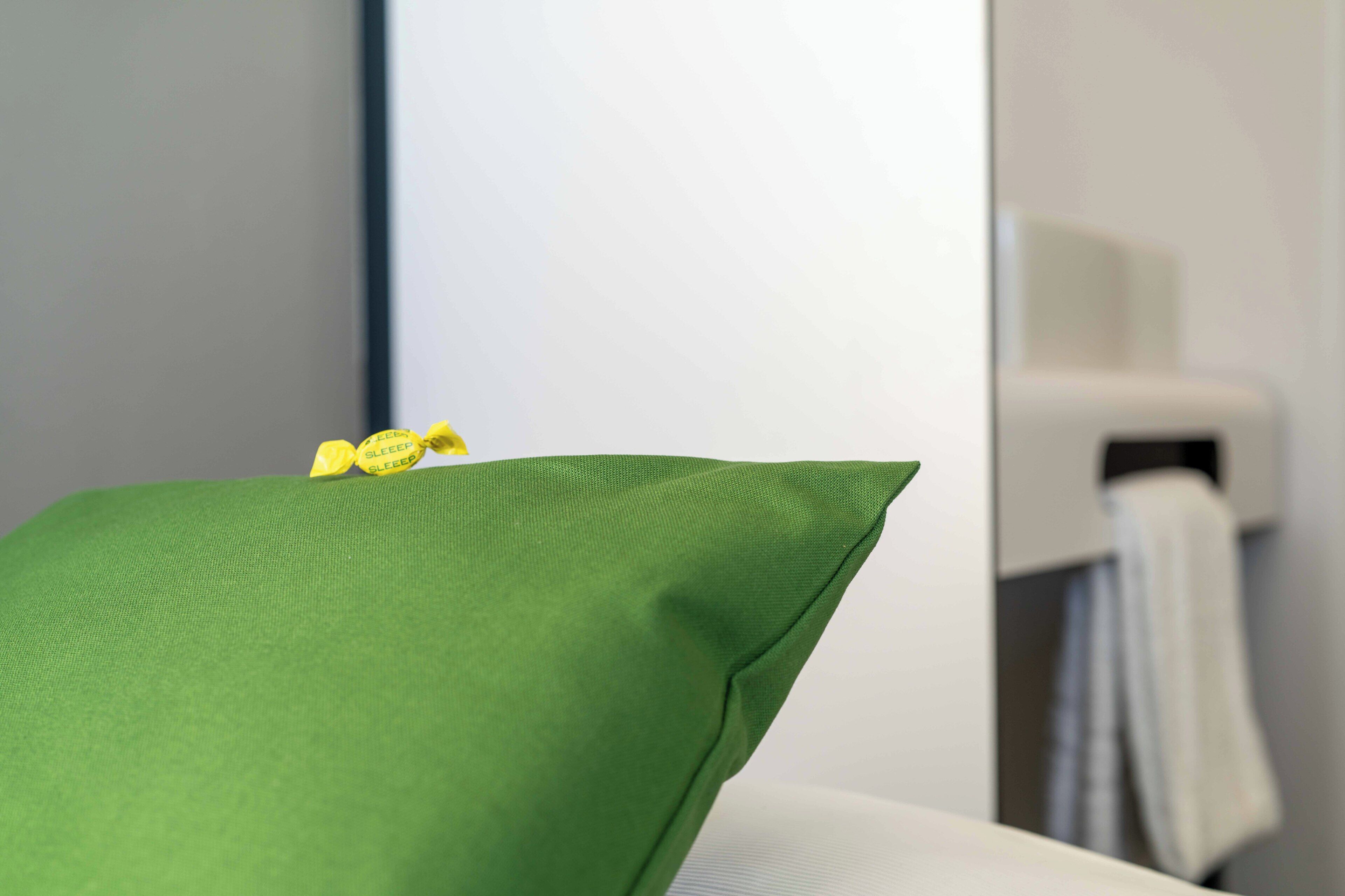 Un cojín verde sobre una silla blanca en un baño.