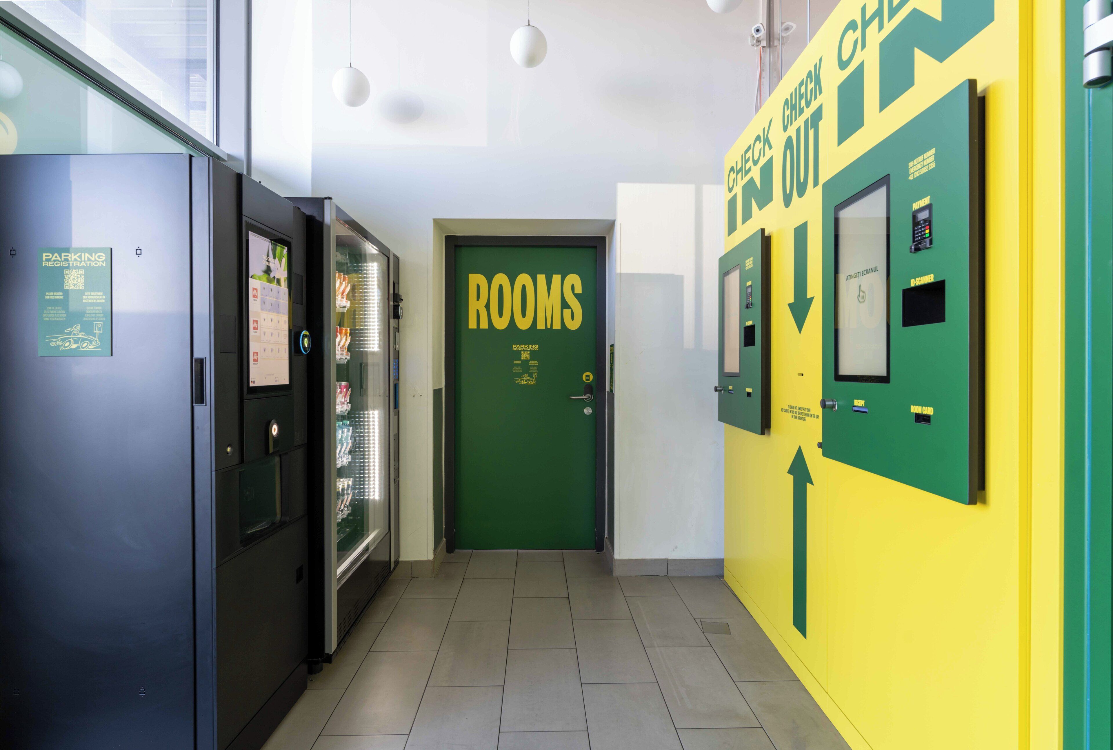 A hotel corridor with a green door labeled 'ROOMS,' a parking sign, and directional arrows on the walls.