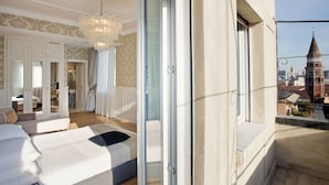 A modern hotel room with a large bed, a chandelier, and a balcony with a city view. - Luxury Suite Milano Duomo (Milan)