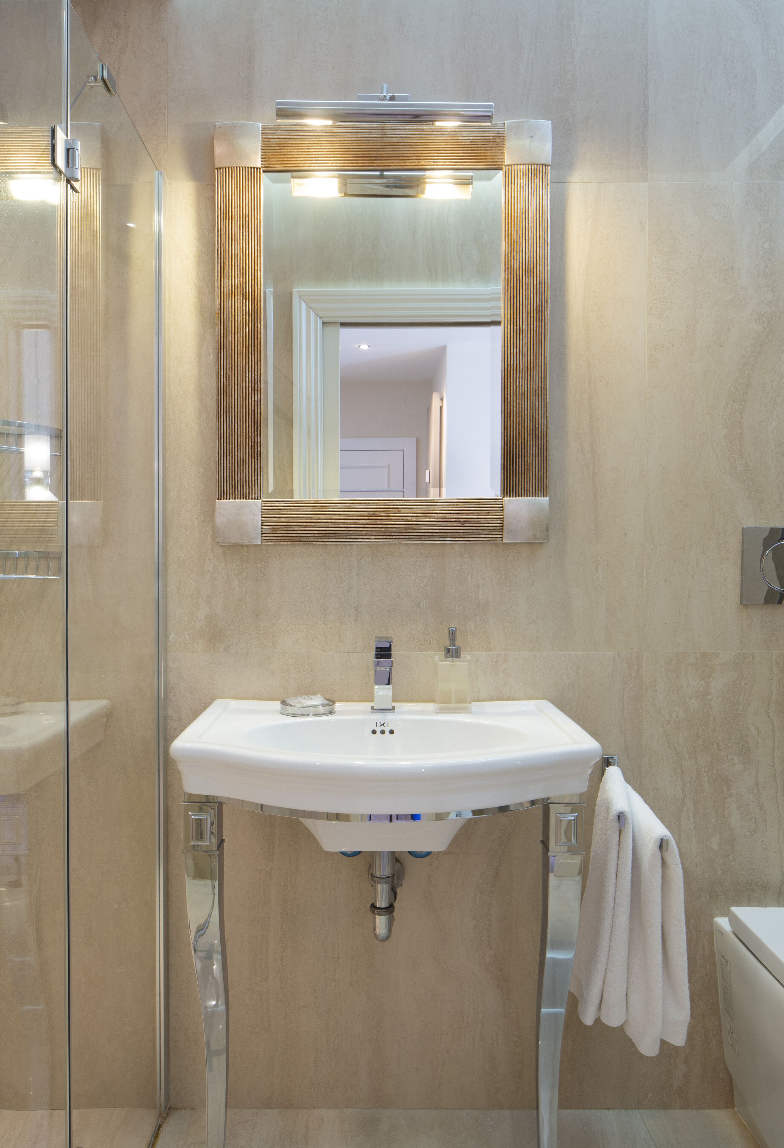 Un bagno moderno con box doccia in vetro, un lavandino bianco con specchio sopra e il water a destra.