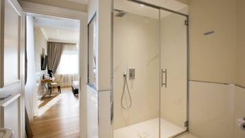 A modern bathroom with a glass shower enclosure, a toilet, and a visible shower control panel.
