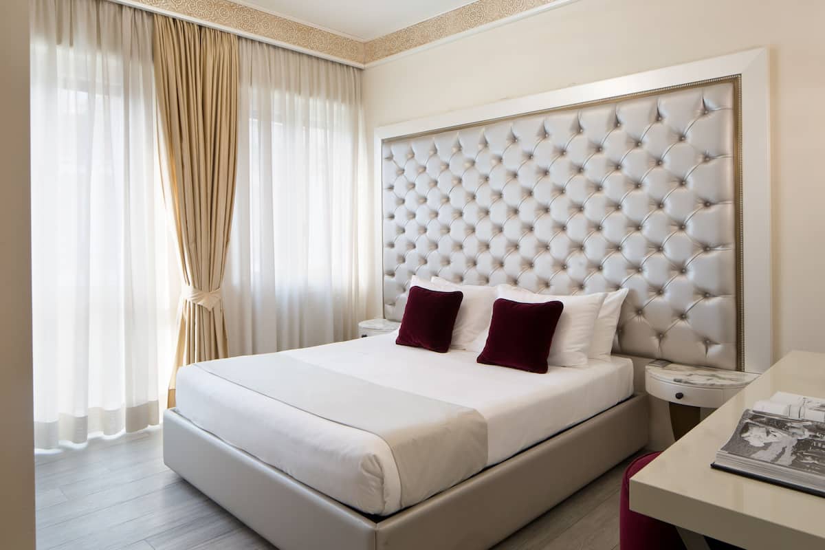 Ein Hotelzimmer mit einem großen Bett, einem gepolsterten Kopfteil, einem Nachttisch und einem Beistelltisch.