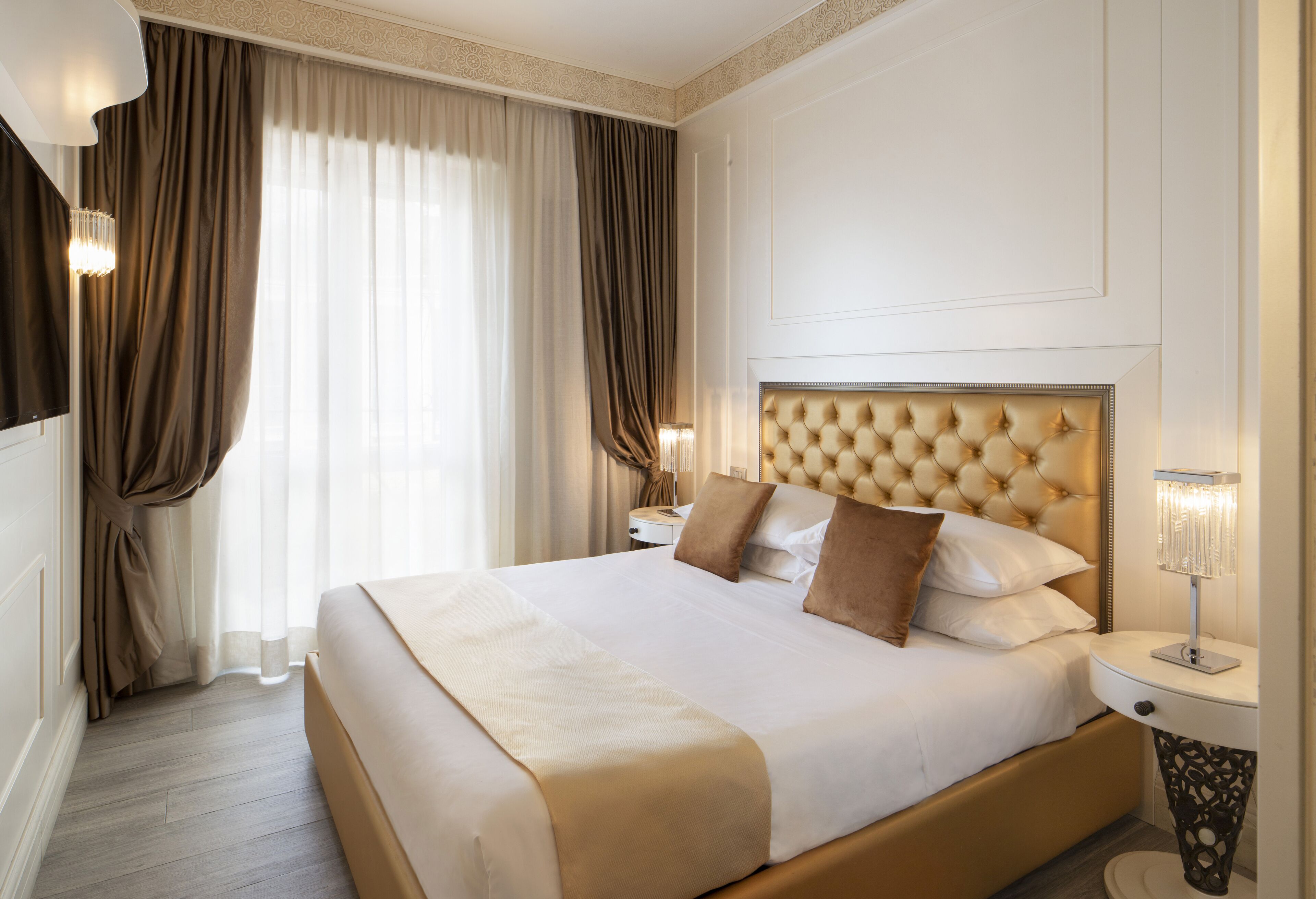 A large bed with a tufted headboard, a bedside lamp, and a nightstand.