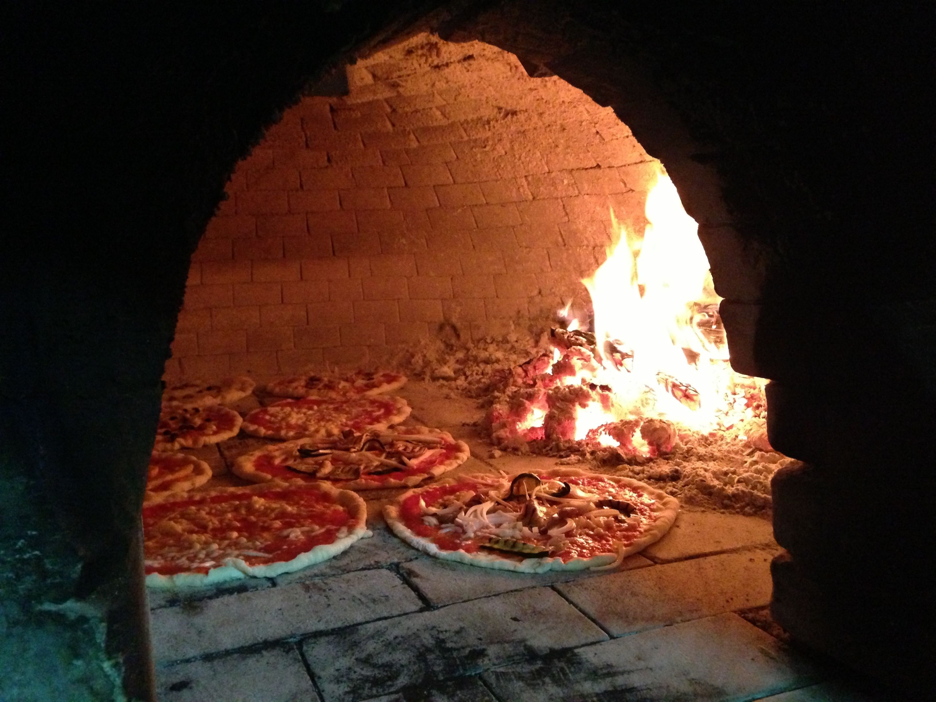 A brick oven with pizzas baking inside.