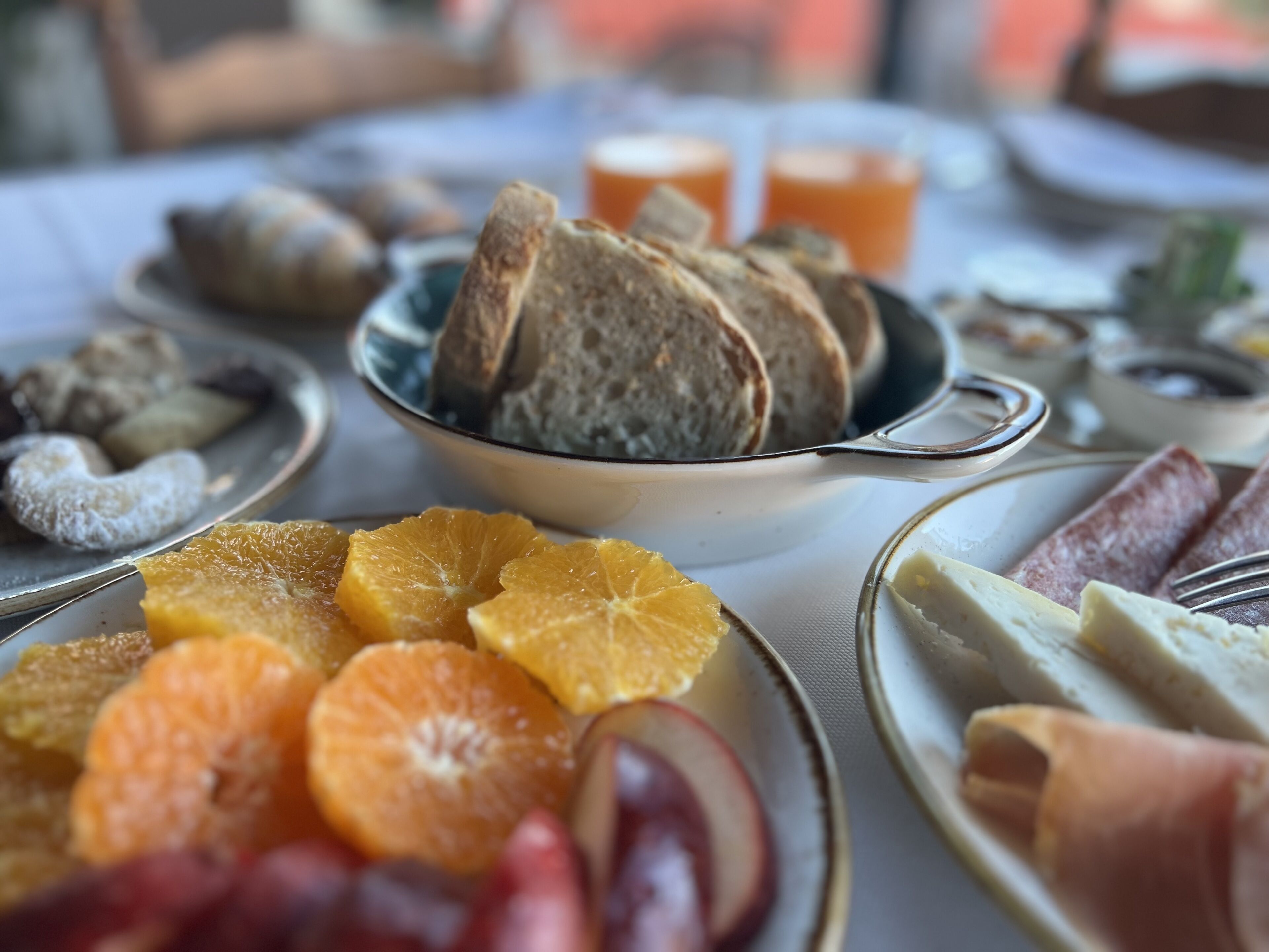 A breakfast setting with bread, fruits, and cheese on plates.
