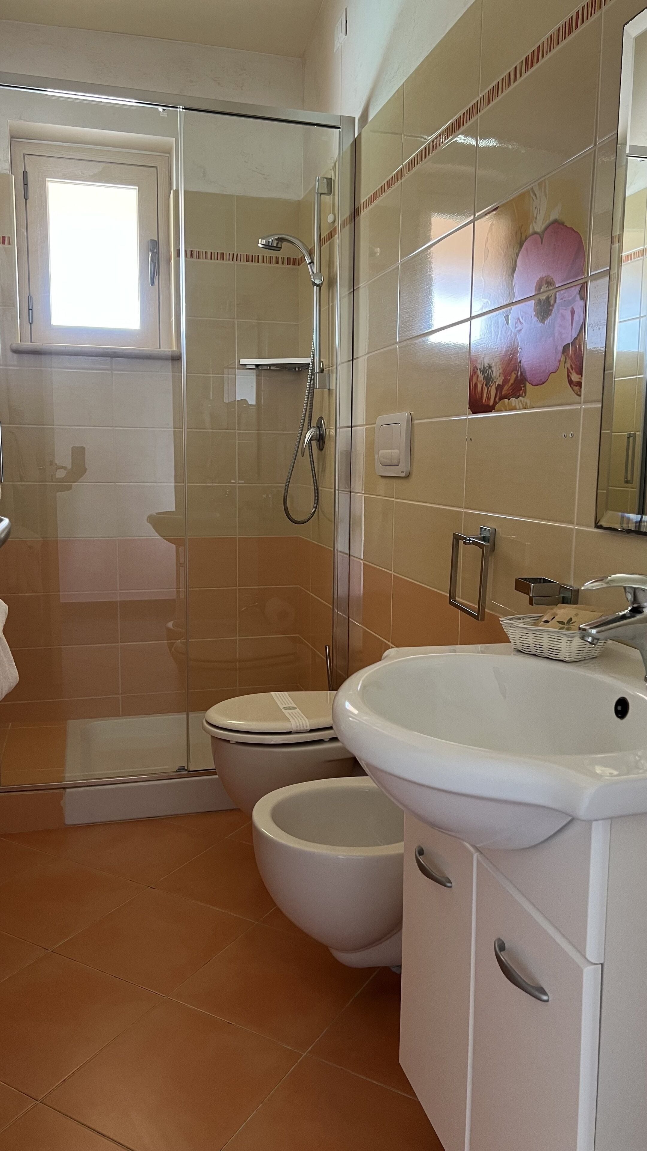 Ein Badezimmer mit Duschkabine, Toilette und Waschbecken mit Spiegel.